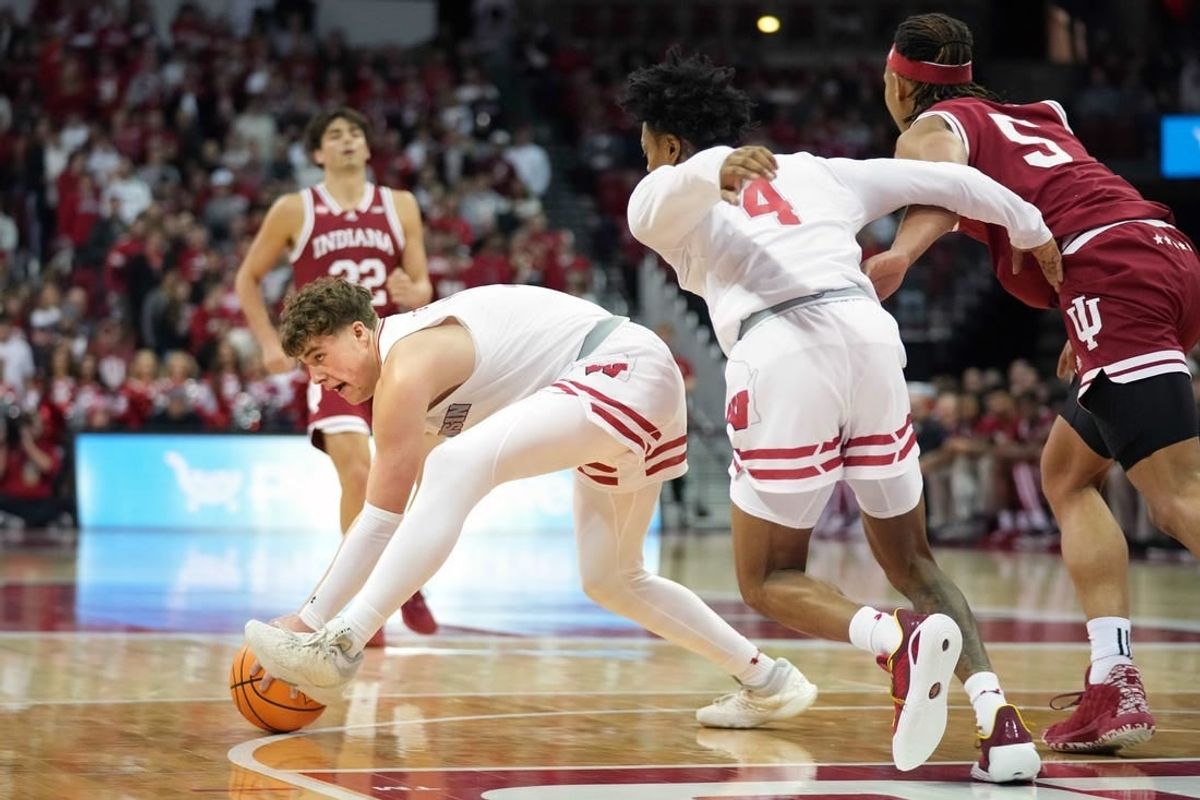 Jan 19, 2024; Madison, Wisconsin, USA; Wisconsin Badgers guard Max Klesmit (11) picks up a loose ball against Indiana Hoosiers forward Malik Reneau (5) and teammate Wisconsin Badgers guard Kamari McGee (4) during the first half at the Kohl Center.