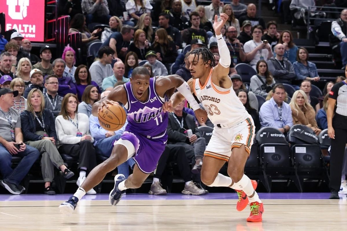 Feb 25, 2024; Salt Lake City, Utah, USA; Utah Jazz guard Kris Dunn (11) drives against San Antonio Spurs guard Tre Jones (33) during the second quarter at Delta Center.