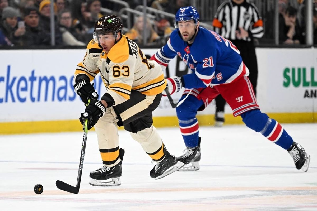 Mar 21, 2024; Boston, Massachusetts, USA; Boston Bruins left wing Brad Marchand (63) skates with the puck against New York Rangers center Barclay Goodrow (21) during the second period at the TD Garden.