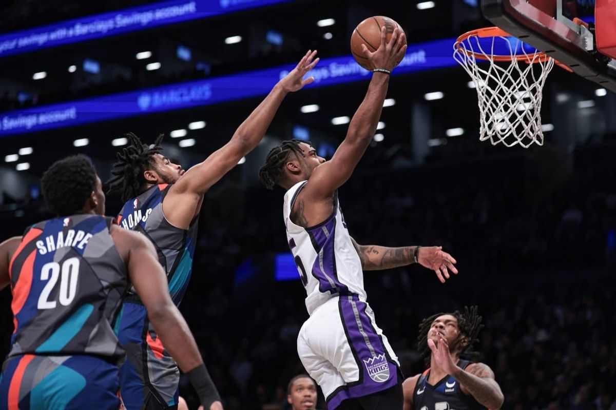 Apr 7, 2024; Brooklyn, New York, USA; Sacramento Kings guard Davion Mitchell (15) drives for a shot against Brooklyn Nets center Day'Ron Sharpe (20) and guard Cam Thomas (24) during the first half at Barclays Center.