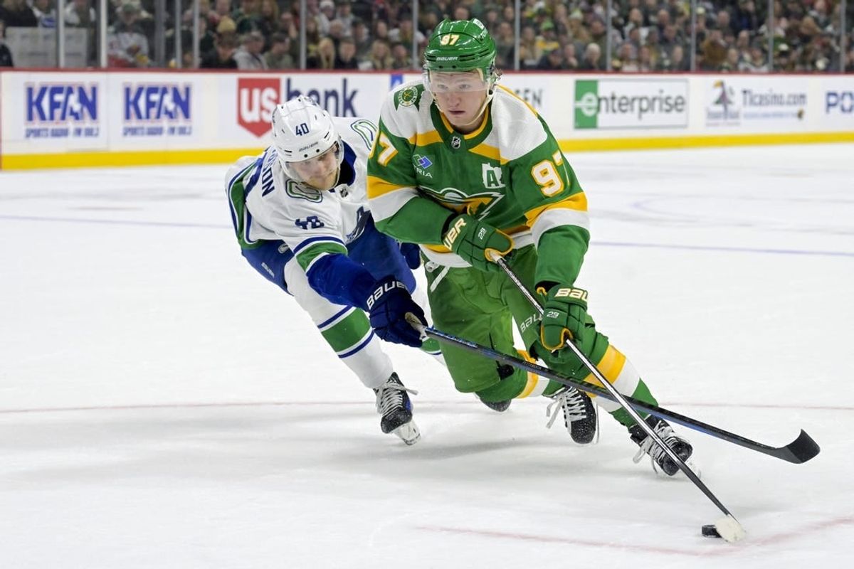 Dec 16, 2023; Saint Paul, Minnesota, USA;  Minnesota Wild forward Kirill Kaprizov (97) controls the puck as Vancouver Canucks forward Elias Pettersson (40) defends during overtime at Xcel Energy Center.