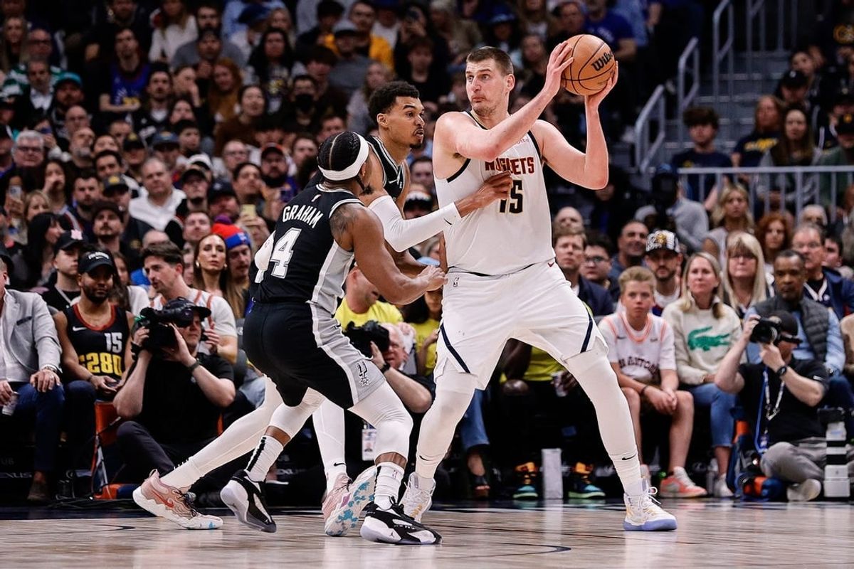Apr 2, 2024; Denver, Colorado, USA; Denver Nuggets center Nikola Jokic (15) controls the ball as San Antonio Spurs center Victor Wembanyama (1) and guard Devonte' Graham (4) defend in the second quarter at Ball Arena.