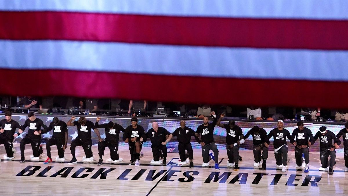 Members of the Magic and Nets kneel before a July 2020 pandemic-era bubble game.