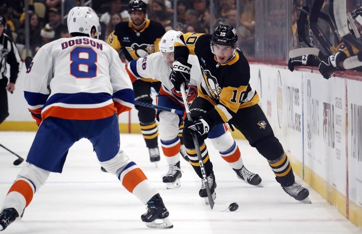 Feb 20, 2024; Pittsburgh, Pennsylvania, USA; Pittsburgh Penguins left wing Drew O'Connor (10) skates up ice with the puck as New York Islanders defenseman Noah Dobson (8) defends during the first period  at PPG Paints Arena.