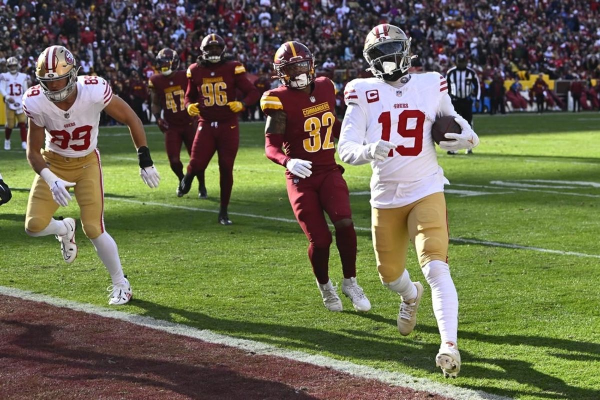Dec 31, 2023; Landover, Maryland, USA; San Francisco 49ers wide receiver Deebo Samuel (19) scores a touchdown  as Washington Commanders safety Terrell Burgess (32) looks on during the first half at FedExField.