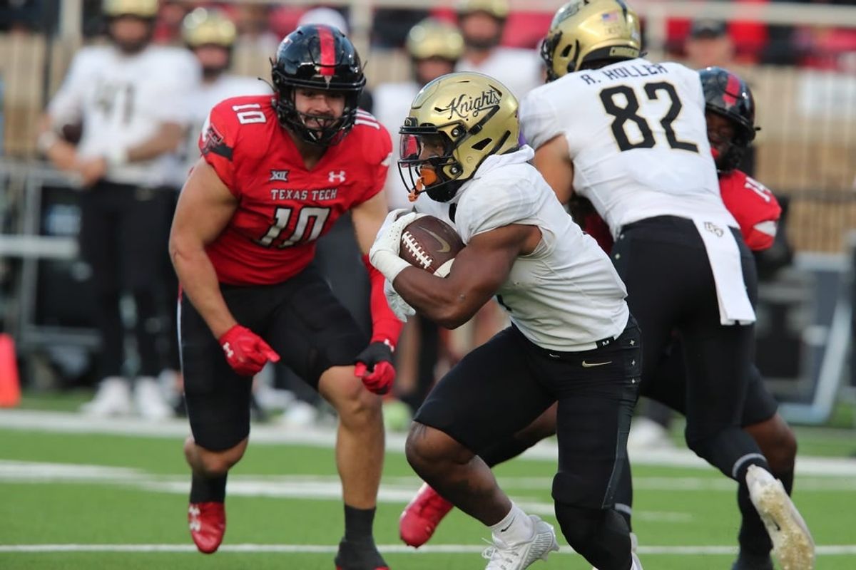 Nov 18, 2023; Lubbock, Texas, USA;  Central Florida Knights running back RJ Harvey (7) rushes against Texas Tech Red Raiders defensive end Jacob Rodriguez (10) in the first half at Jones AT&T Stadium and Cody Campbell Field.
