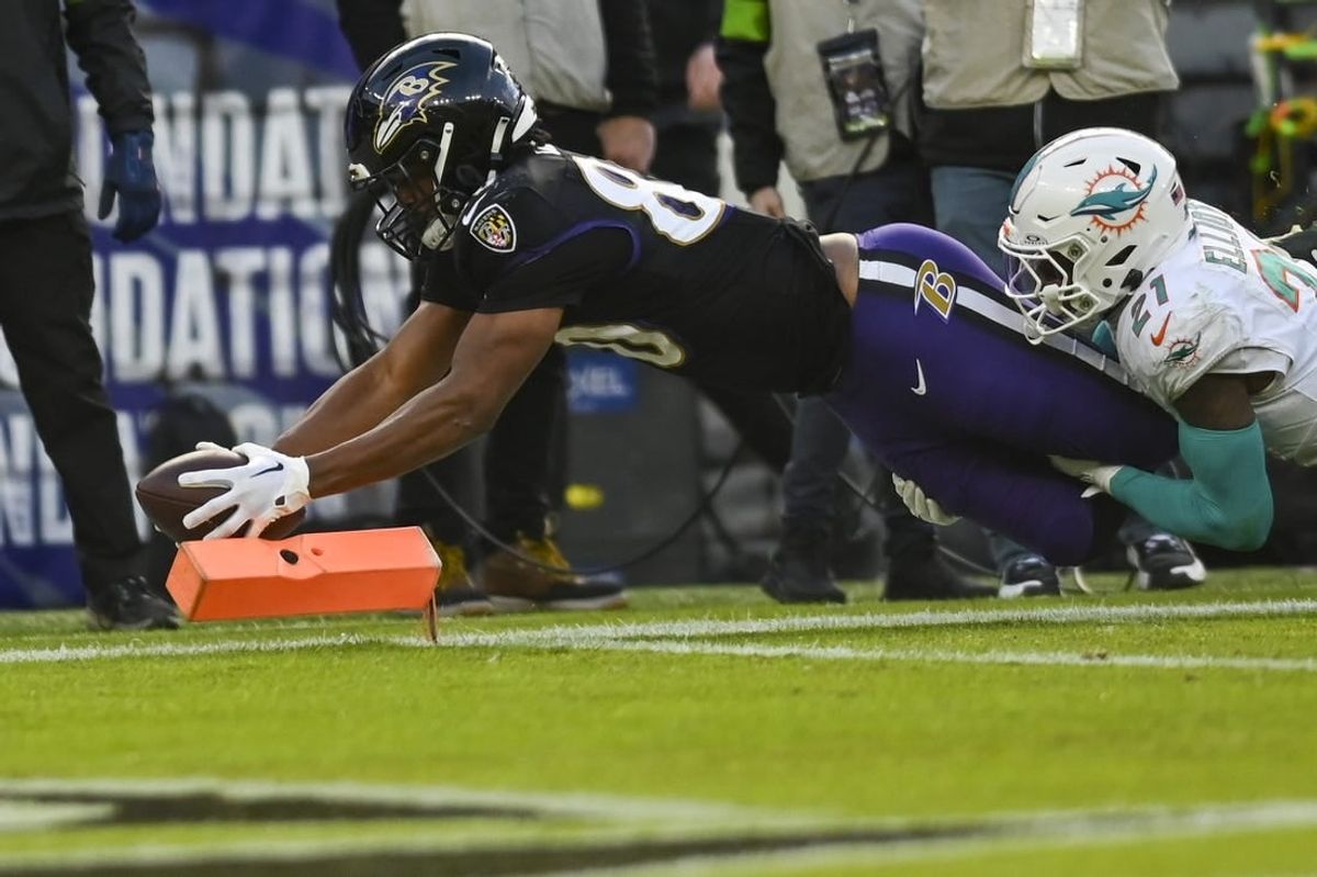 Dec 31, 2023; Baltimore, Maryland, USA;  Baltimore Ravens tight end Isaiah Likely (80) dives for a touchdown  as Miami Dolphins safety DeShon Elliott (21) defends during the first half at M&T Bank Stadium.