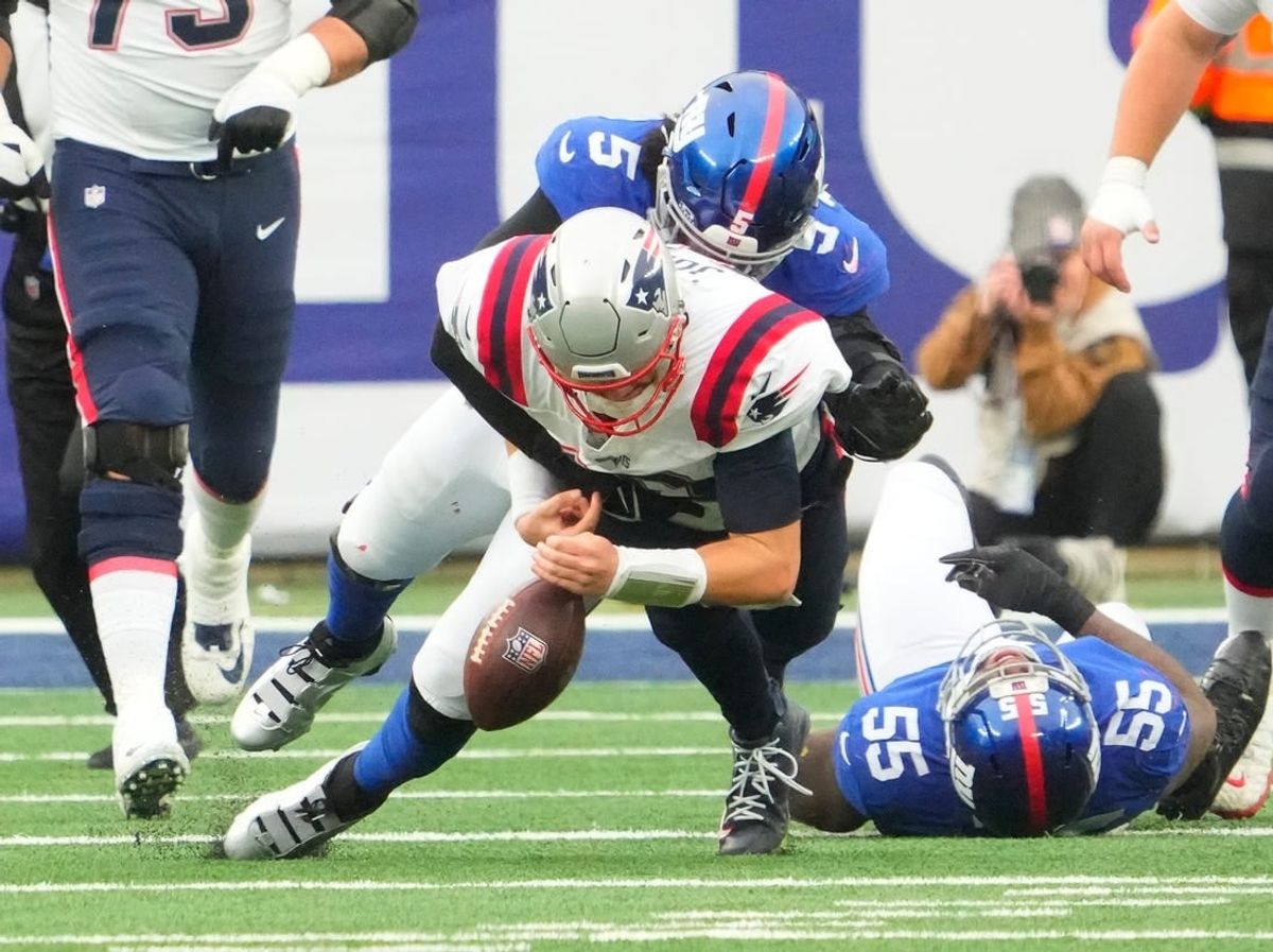 Nov 26, 2023; East Rutherford, New Jersey, USA; New England Patriots quarterback Mac Jones (10) loses the ball as he is tackled by New York Giants linebacker Jihad Ward (55), but the Patriots recovered, at MetLife Stadium.