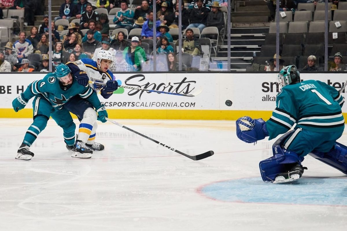 Apr 6, 2024; San Jose, California, USA; St. Louis Blues center Brayden Schenn (10) shoots the puck against San Jose Sharks goaltender Devin Cooley (1) and defenseman Kyle Burroughs (4) during the third period at SAP Center at San Jose.