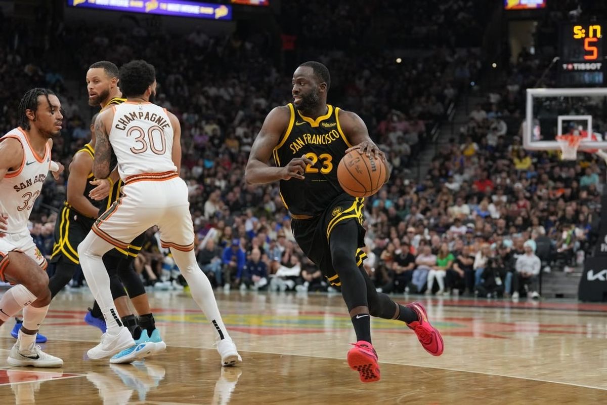 Mar 31, 2024; San Antonio, Texas, USA;  Golden State Warriors forward Draymond Green (23) dribbles past San Antonio Spurs forward Julian Champagnie (30) in the first half at Frost Bank Center.