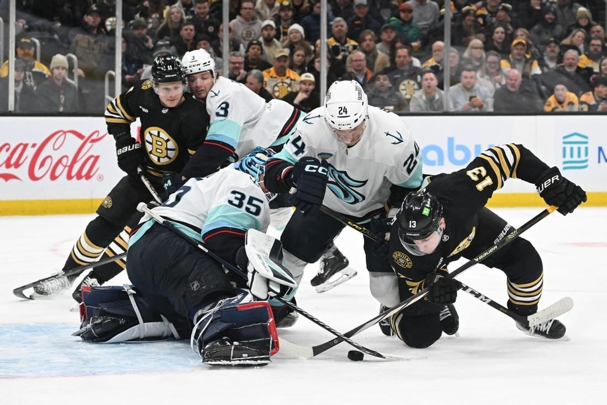 Feb 15, 2024; Boston, Massachusetts, USA; Boston Bruins center Charlie Coyle (13) battles for the puck against Seattle Kraken goaltender Joey Daccord (35) and defenseman Jamie Oleksiak (24) during the first period at TD Garden.
