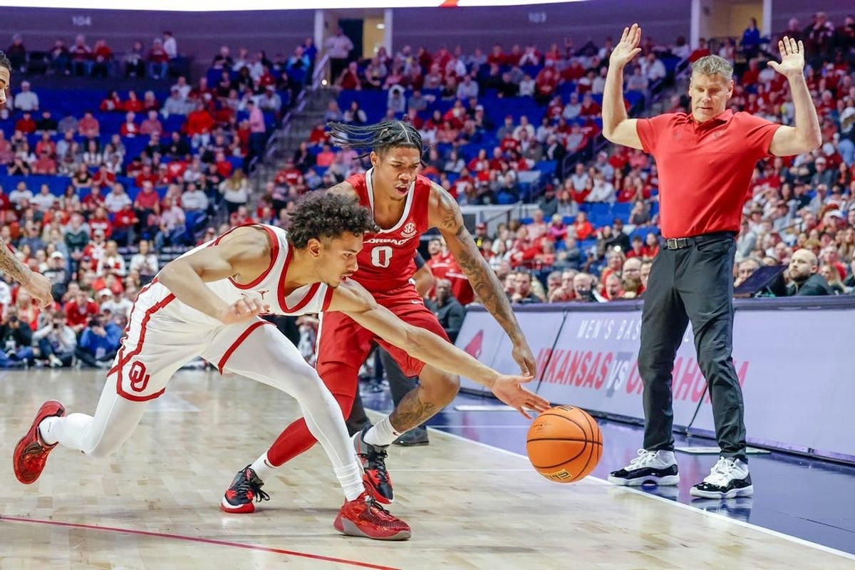 Oklahoma guard Milos Uzan (12) and Arkansas guard Khalif Battle (0) fight for a ball going out-of-bounds during an NCAA basketball game between the Oklahoma Sooners and the Arkansas Razorbacks at the BOK Center in Tulsa, Okla., on Saturday, Dec. 9, 2023.