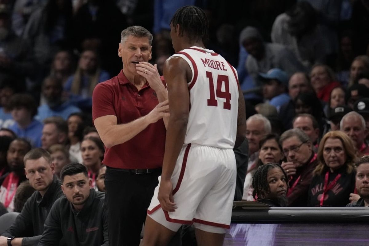 Dec 20, 2023; Charlotte, North Carolina, USA; Oklahoma Sooners head coach Porter Moser talks with forward Jalon Moore (14) during a time out against the North Carolina Tar Heels during the first half at Spectrum Center.