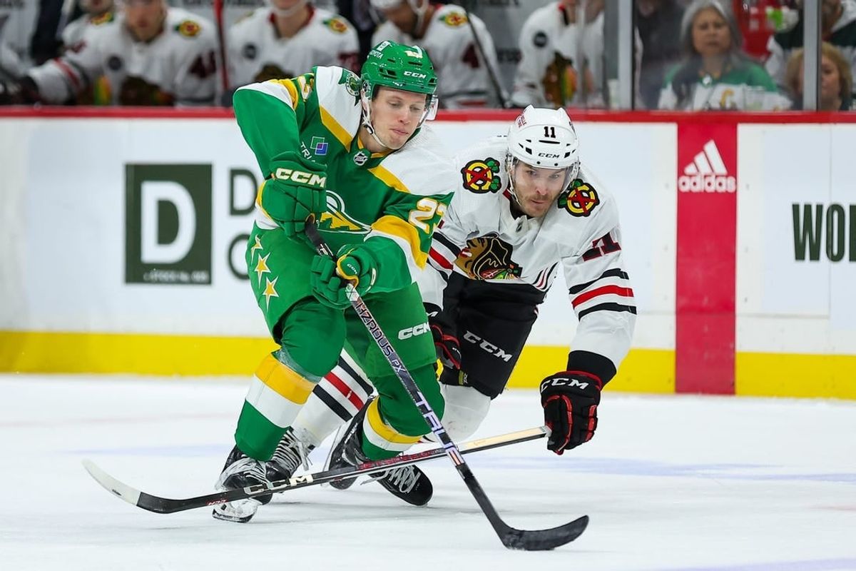 Dec 3, 2023; Saint Paul, Minnesota, USA; Minnesota Wild center Marco Rossi (23) and Chicago Blackhawks right wing Taylor Raddysh (11) compete for the puck during the second period at Xcel Energy Center.
