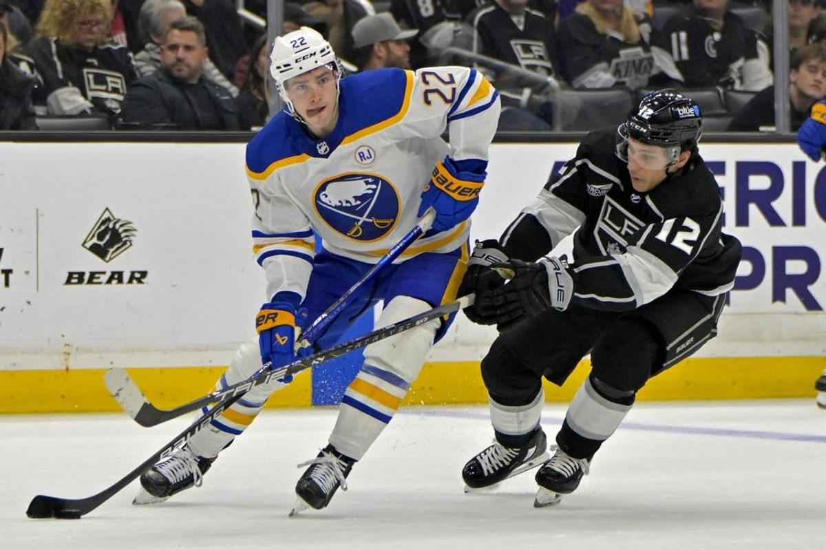 Jan 24, 2024; Los Angeles, California, USA; Buffalo Sabres right wing Jack Quinn (22) handles the puck as he is defended by Los Angeles Kings left wing Trevor Moore (12) in the second period at Crypto.com Arena.