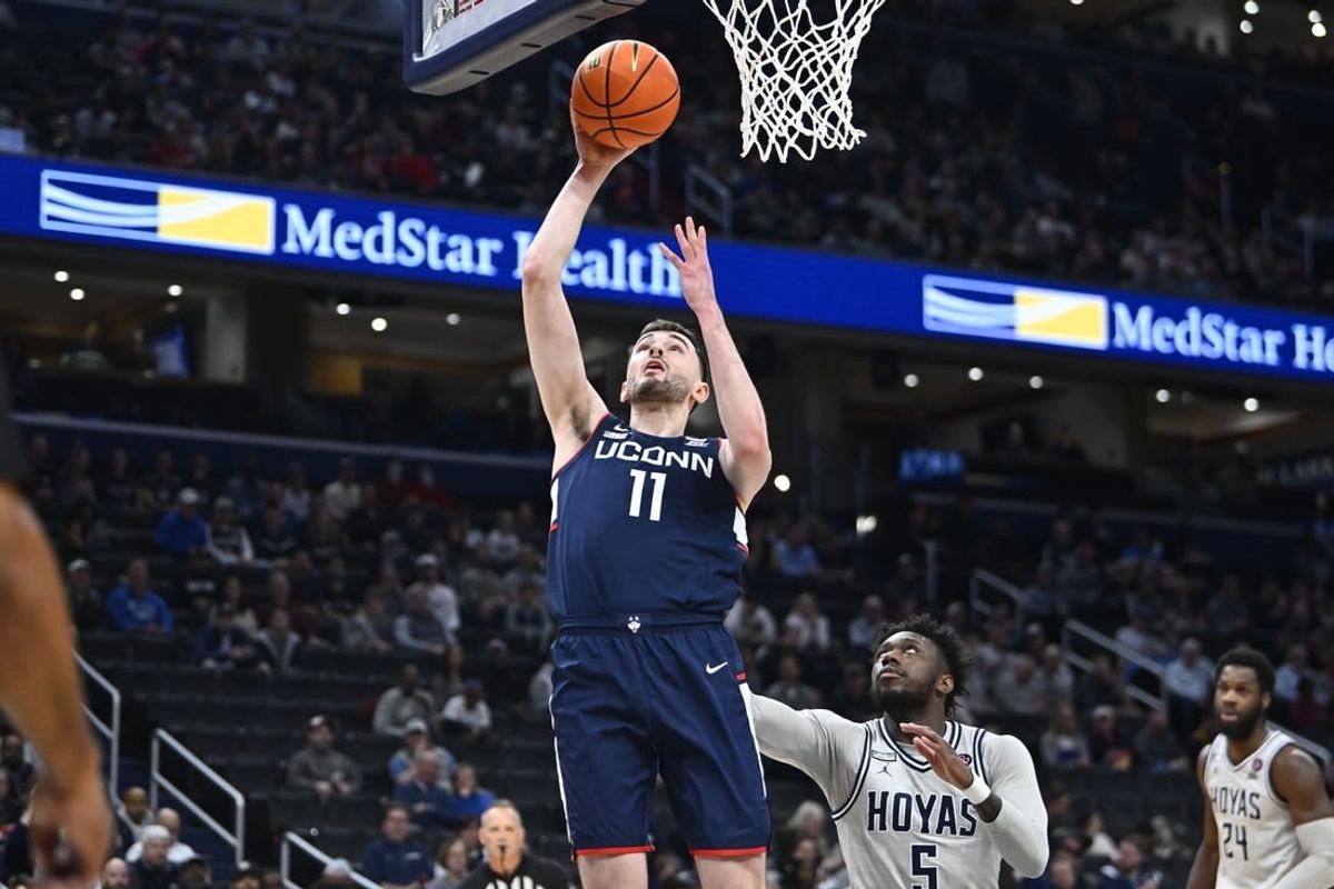 Feb 10, 2024; Washington, District of Columbia, USA; Connecticut Huskies forward Alex Karaban (11) shoots as Georgetown Hoyas guard Jay Heath (5) looks on during the first half at Capital One Arena.
