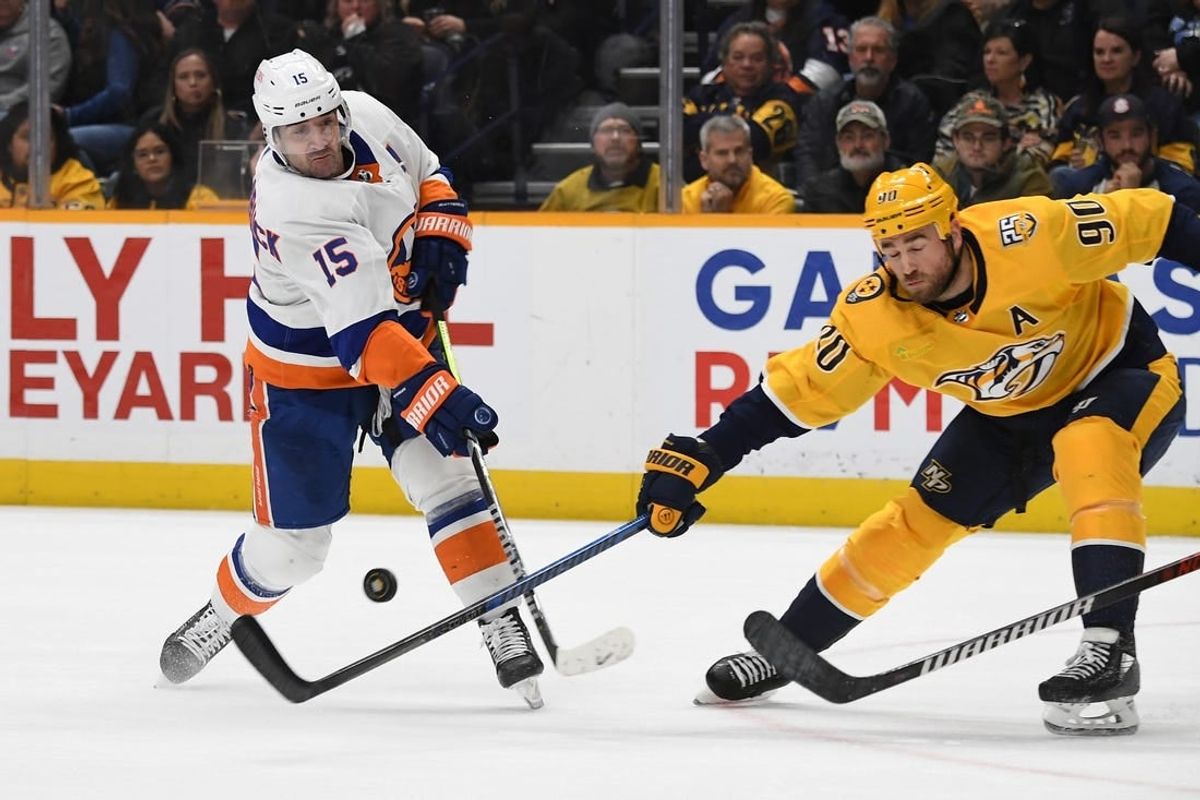 Jan 13, 2024; Nashville, Tennessee, USA; New York Islanders right wing Cal Clutterbuck (15) shoots the puck against Nashville Predators center Ryan O'Reilly (90) during the second period at Bridgestone Arena.