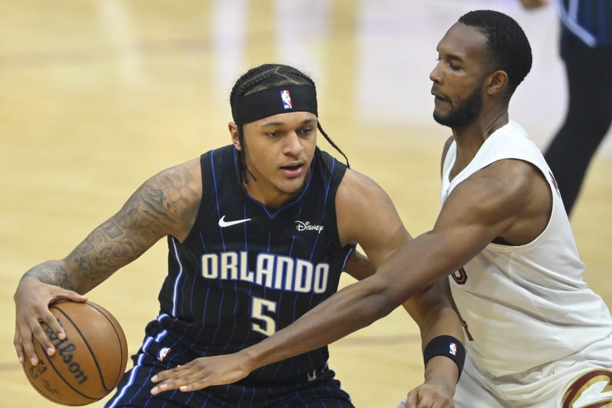 Feb 22, 2024; Cleveland, Ohio, USA; Orlando Magic forward Paolo Banchero (5) dribbles beside Cleveland Cavaliers forward Evan Mobley (4) in the first quarter at Rocket Mortgage FieldHouse.