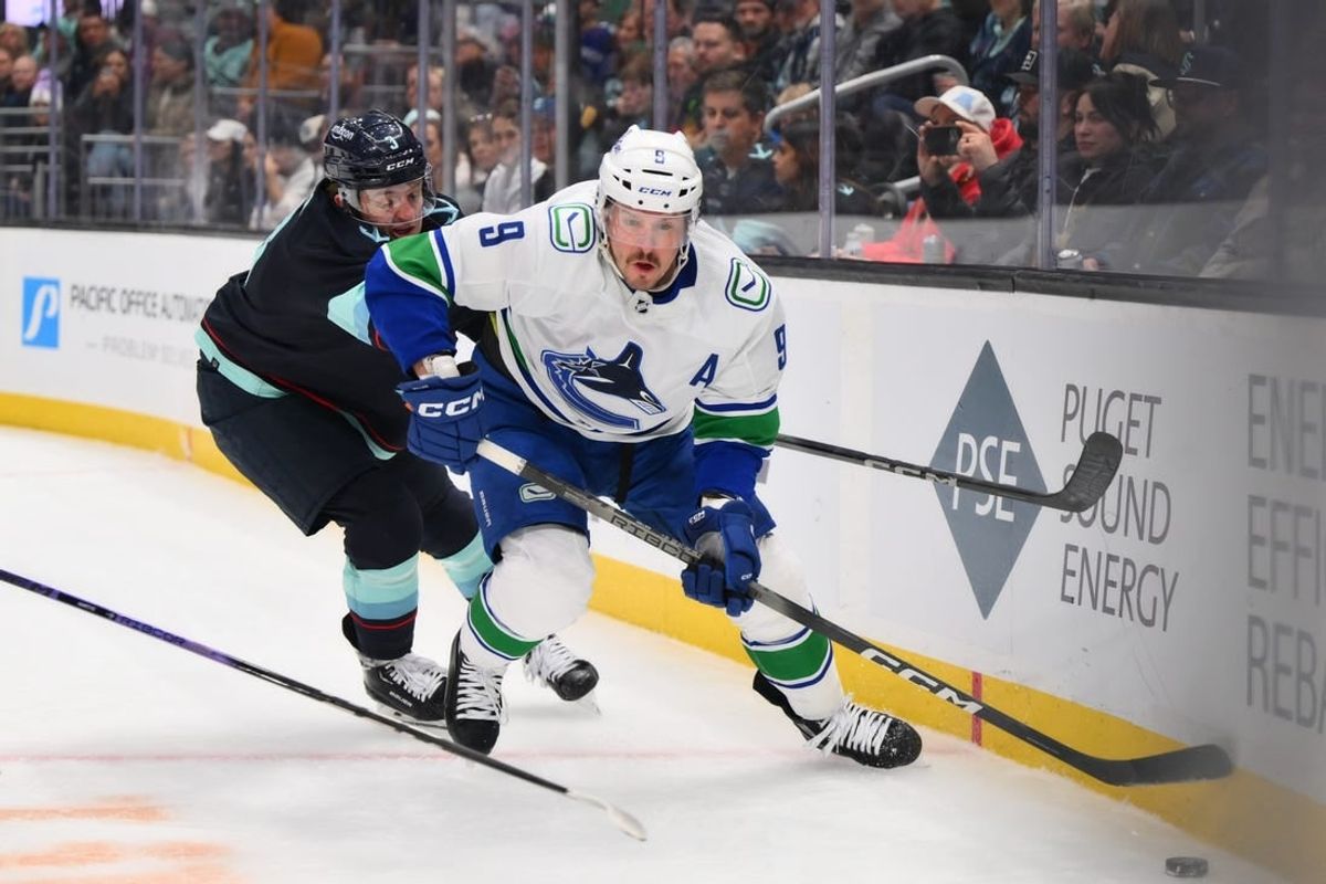 Feb 22, 2024; Seattle, Washington, USA; Vancouver Canucks center J.T. Miller (9) plays the puck while defended by Seattle Kraken defenseman Will Borgen (3) during the first period at Climate Pledge Arena.