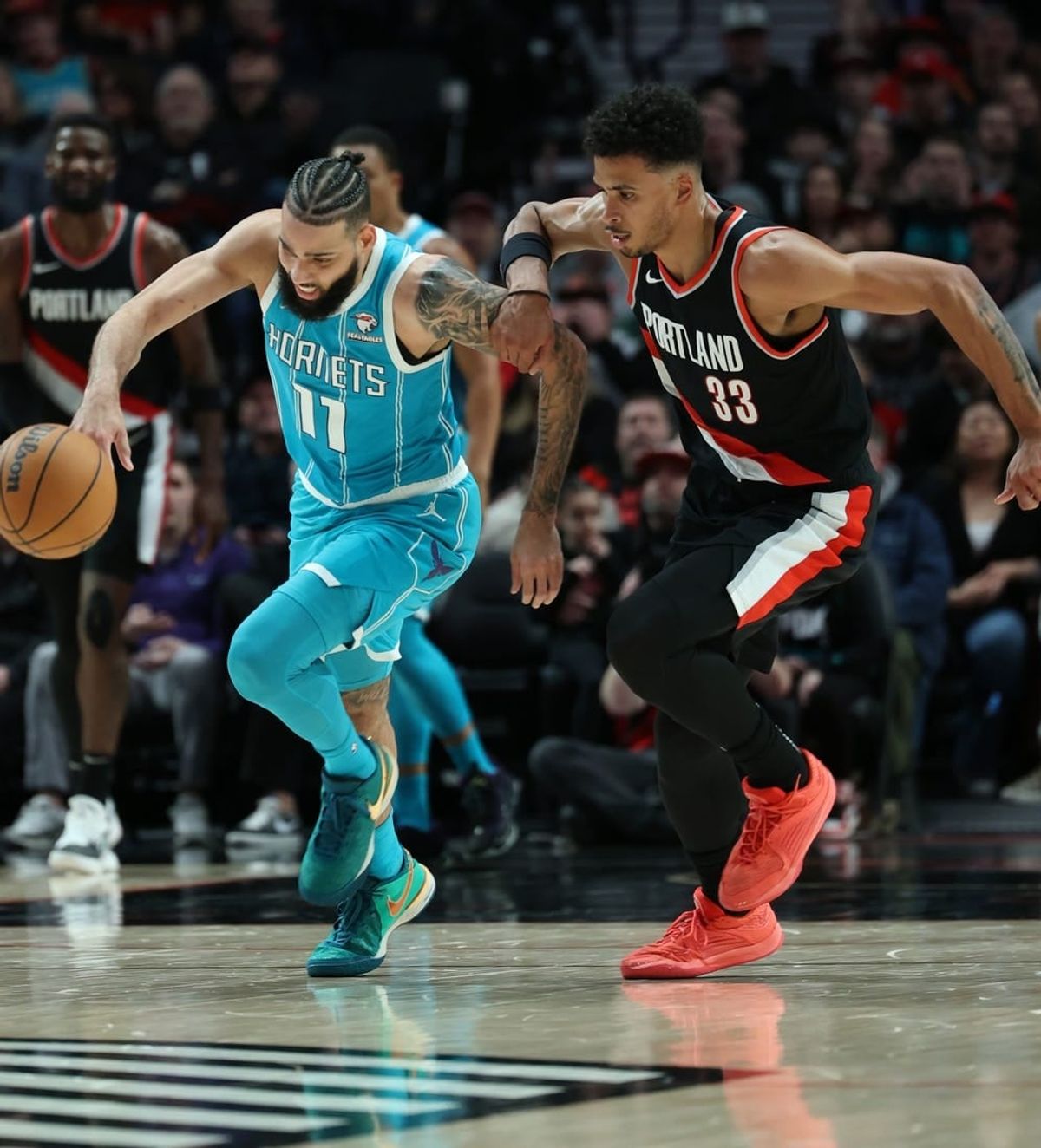 Feb 25, 2024; Portland, Oregon, USA; Charlotte Hornets forward Cody Martin (11) advances the ball past Portland Trail Blazers forward Toumani Camara (33) in the second quarter at Moda Center.