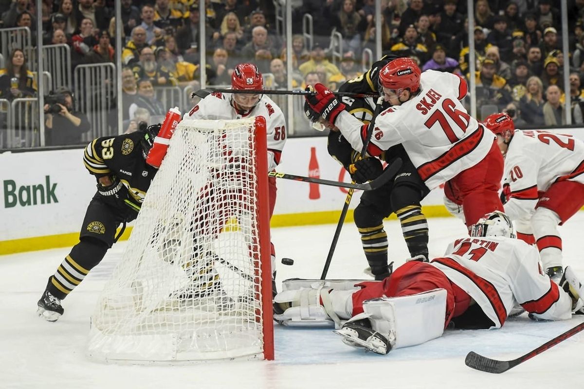 Jan 24, 2024; Boston, Massachusetts, USA; Boston Bruins right wing David Pastrnak (88) tries to bat the puck past Carolina Hurricanes goaltender Spencer Martin (41) while defenseman Brady Skjei (76) defends during the first period at TD Garden.