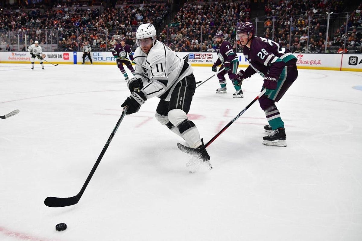 Apr 9, 2024; Anaheim, California, USA; Los Angeles Kings center Anze Kopitar (11) moves the puck ahead of Anaheim Ducks defenseman Gustav Lindstrom (28) during the third period at Honda Center.