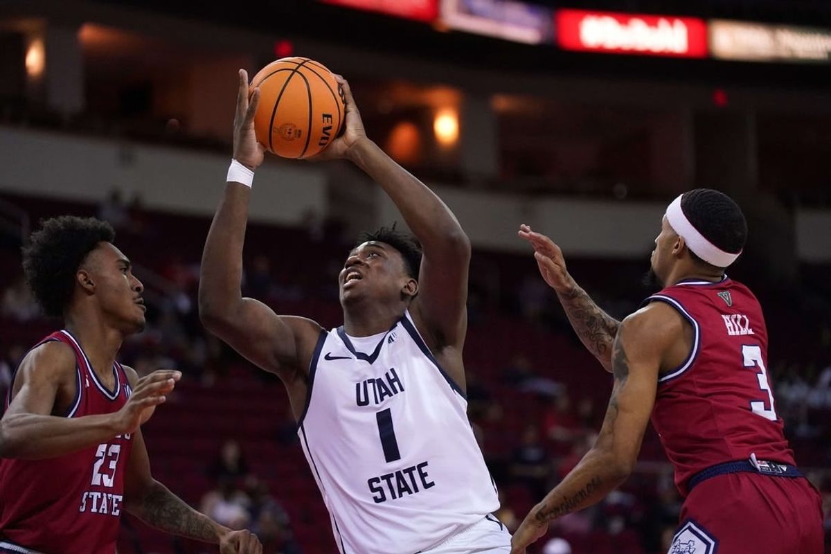 Feb 27, 2024; Fresno, California, USA; Utah State Aggies forward Great Osobor (1) drives to the hoop between Fresno State Bulldogs guard Leo Colimerio (23) and guard Isaiah Hill (3) in the first half at the Save Mart Center.