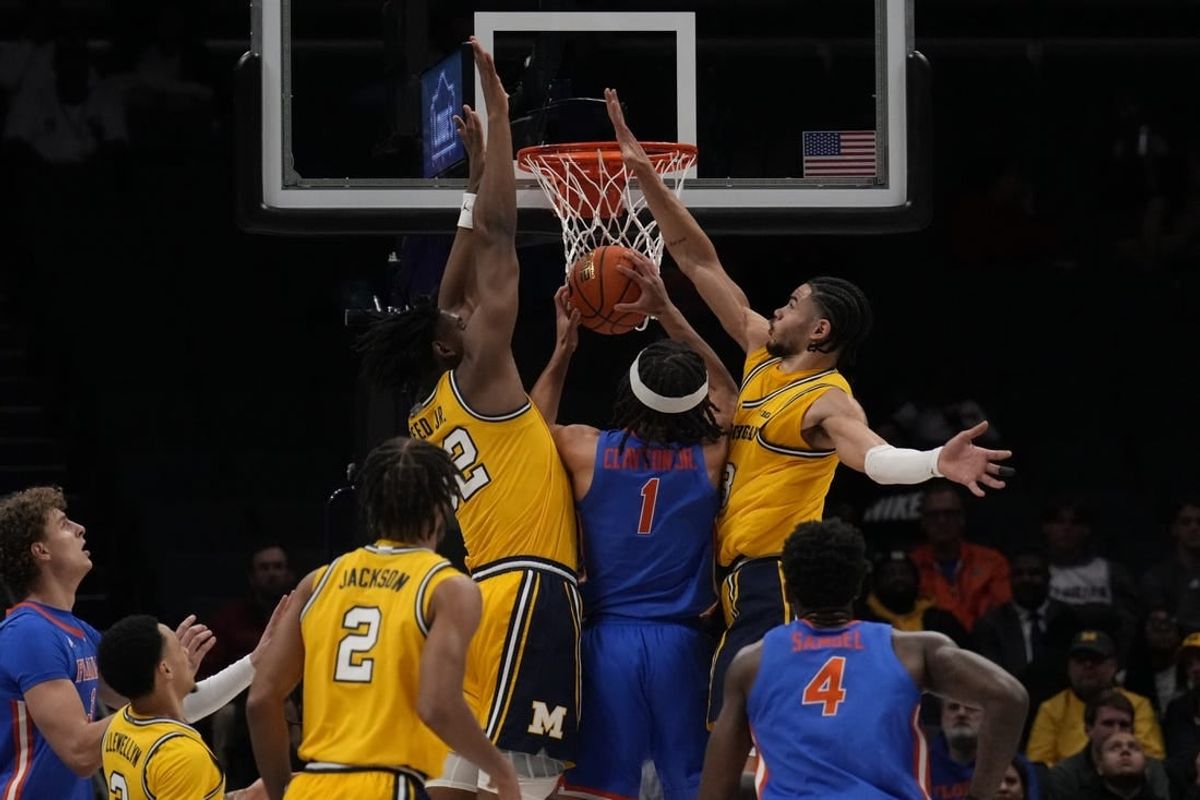 Dec 19, 2023; Charlotte, North Carolina, USA; Florida Gators guard Walter Clayton Jr. (1) is sandwiched at the basket by Michigan Wolverines forward Tarris Reed Jr. (32) and forward Olivier Nkamhoua (13) during the first half at Spectrum Center.