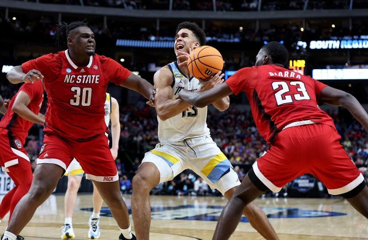 Mar 29, 2024; Dallas, TX, USA; North Carolina State Wolfpack forward Mohamed Diarra (23) knocks the ball away from Marquette Golden Eagles forward Oso Ighodaro (13) as North Carolina State Wolfpack forward DJ Burns Jr. (30) defends during the second half in the semifinals of the South Regional of the 2024 NCAA Tournament at American Airlines Center.