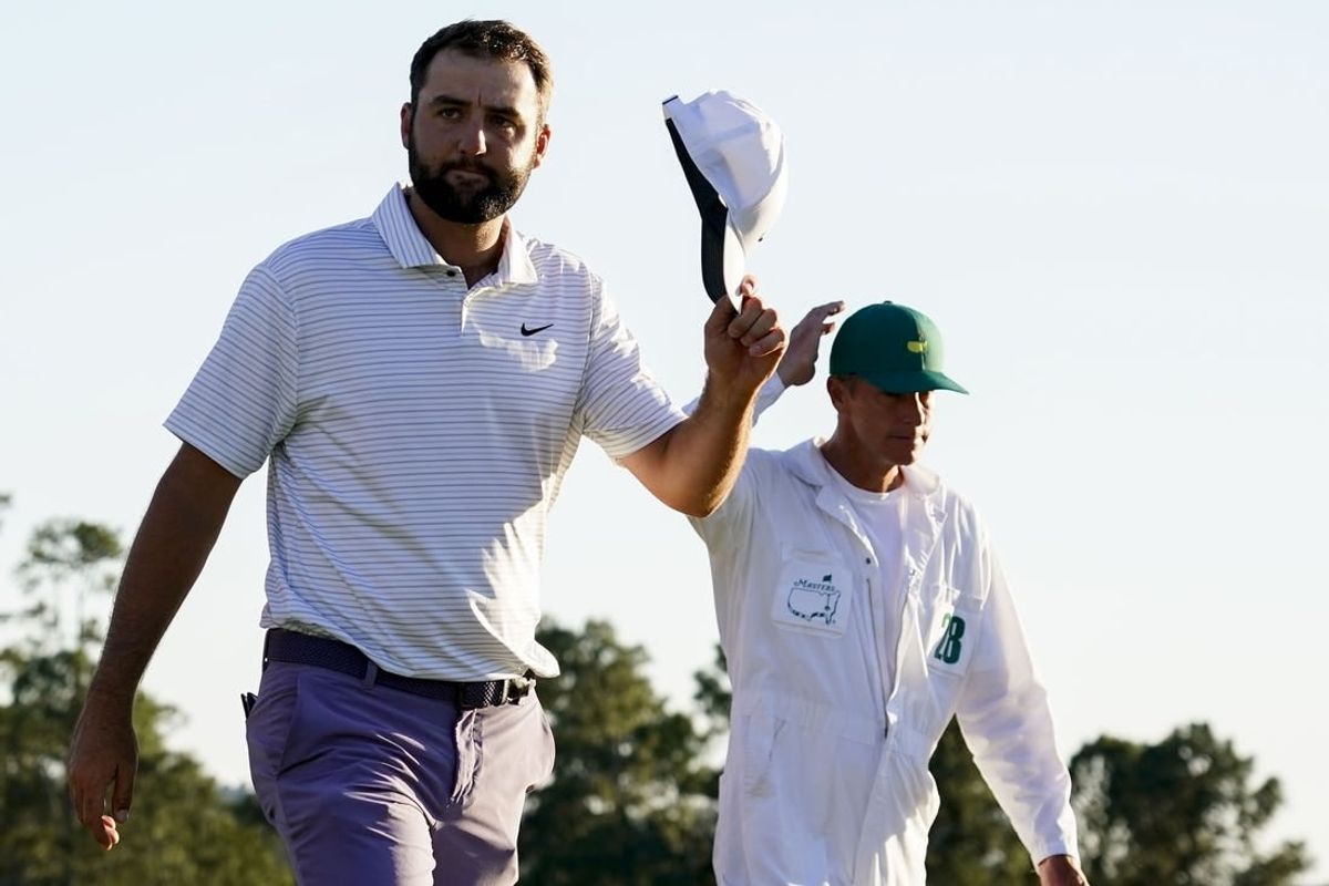 Apr 13, 2024; Augusta, Georgia, USA; Scottie Scheffler tips his hat to patrons as he walks off the No. 18 green during the third round of the Masters Tournament.