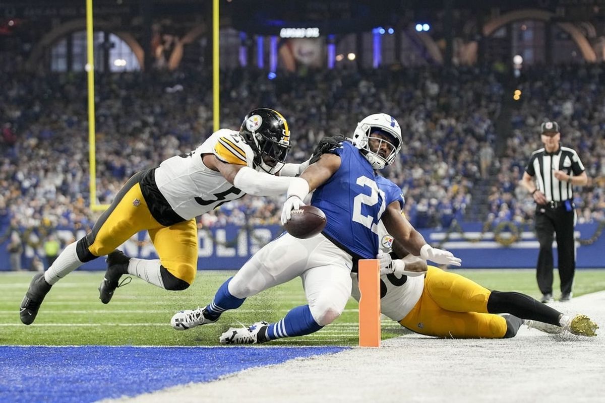 Dec 16, 2023; Indianapolis, Indiana, USA; Indianapolis Colts running back Zack Moss (21) slides into the end zone for a touchdown while being chased by Pittsburgh Steelers linebacker Elandon Roberts (50) and Pittsburgh Steelers linebacker Mykal Walker (38) during a game against the Pittsburgh Steelers at Lucas Oil Stadium.