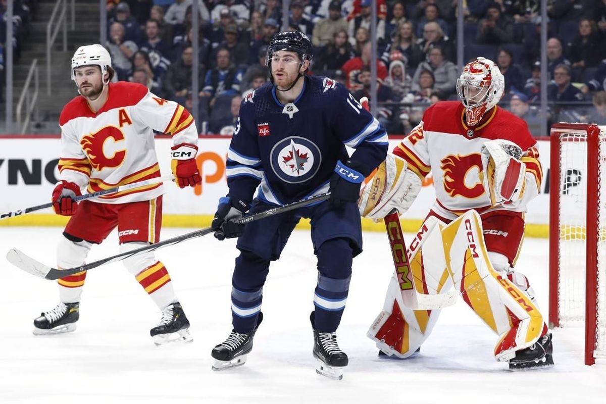 Apr 4, 2024; Winnipeg, Manitoba, CAN; Calgary Flames defenseman Rasmus Andersson (4), Winnipeg Jets center Gabriel Vilardi (13) and Calgary Flames goaltender Dustin Wolf (32) watch the play in the second period at Canada Life Centre.