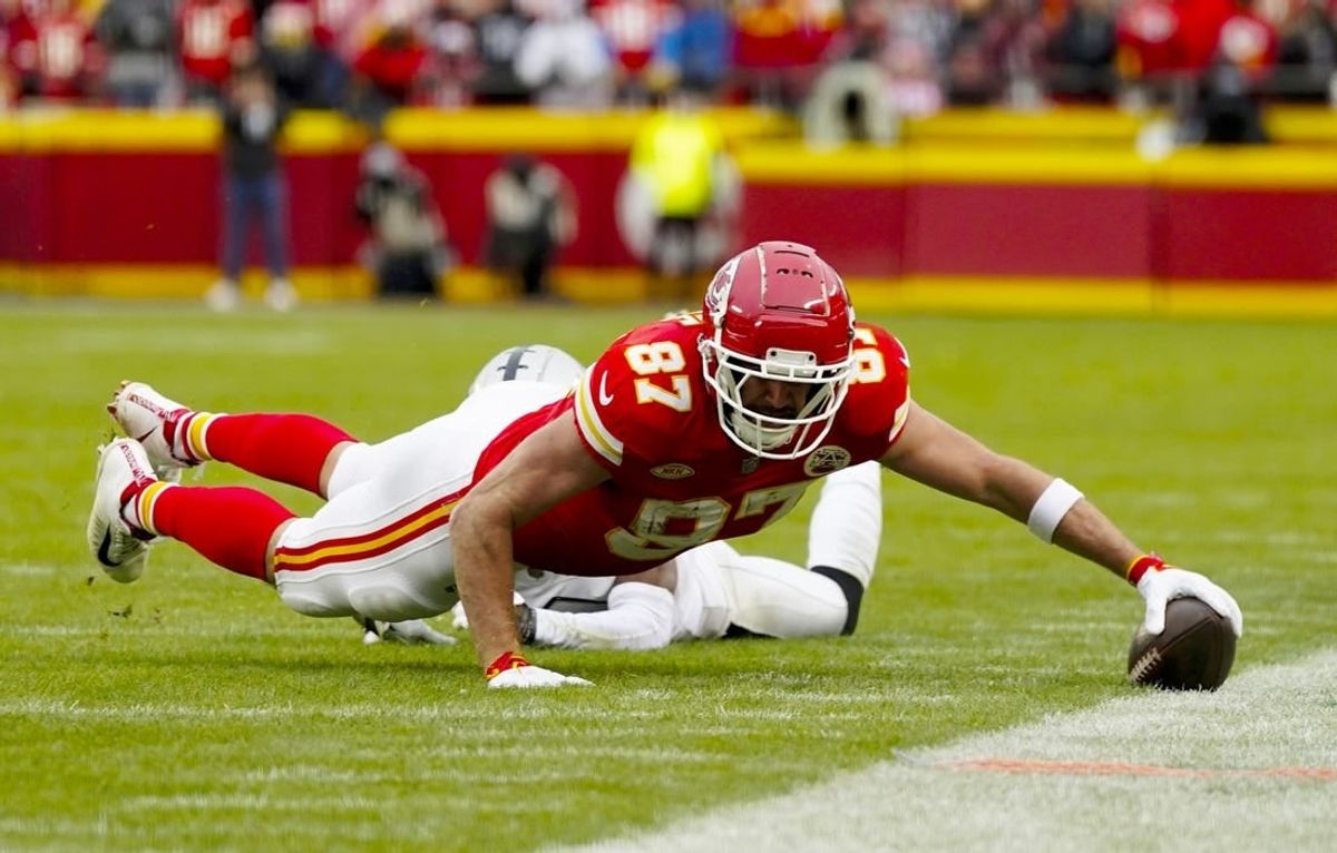 Dec 25, 2023; Kansas City, Missouri, USA; Kansas City Chiefs tight end Travis Kelce (87) dives for the sideline against Las Vegas Raiders cornerback Nate Hobbs (39) during the first half at GEHA Field at Arrowhead Stadium.