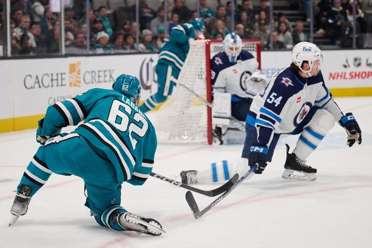 Dec 12, 2023; San Jose, California, USA; San Jose Sharks right wing Kevin Labanc (62) shoots the puck against Winnipeg Jets defenseman Dylan Samberg (54) and goaltender Laurent Brossoit (39) during the second period at SAP Center at San Jose.