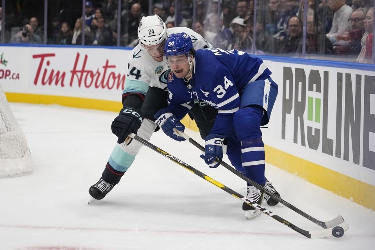 Nov 30, 2023; Toronto, Ontario, CAN; Toronto Maple Leafs forward Auston Matthews (34) battles with Seattle Kracken defenseman Jamie Oleksiak (24) for the puck during the first period at Scotiabank Arena.