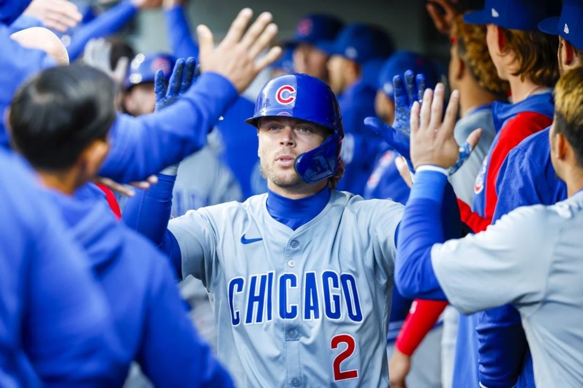 Apr 13, 2024; Seattle, Washington, USA; Chicago Cubs second baseman Nico Hoerner (2) high-fives teammates in the dugout after hitting an RBI-sacrifice fly against the Seattle Mariners during the second inning at T-Mobile Park.