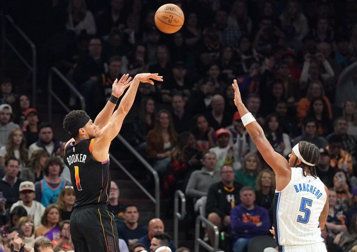 Dec 31, 2023; Phoenix, Arizona, USA; Phoenix Suns guard Devin Booker (1) shoots over Orlando Magic forward Paolo Banchero (5) during the second half at Footprint Center.