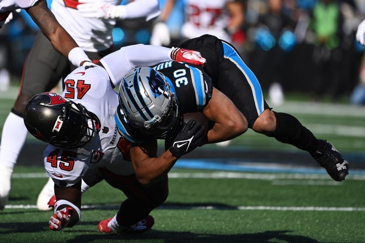 Jan 7, 2024; Charlotte, North Carolina, USA; Carolina Panthers running back Chuba Hubbard (30) is tackled by Tampa Bay Buccaneers linebacker Devin White (45) in the first quarter at Bank of America Stadium.