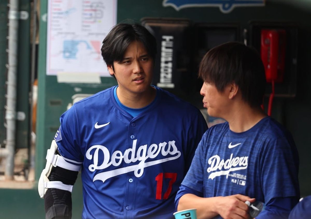 Mar 12, 2024; Phoenix, Arizona, USA; Los Angeles Dodgers designated hitter Shohei Ohtani talks with translator Ippei Mizuhara in the dugout against the San Francisco Giants during a spring training baseball game at Camelback Ranch-Glendale.