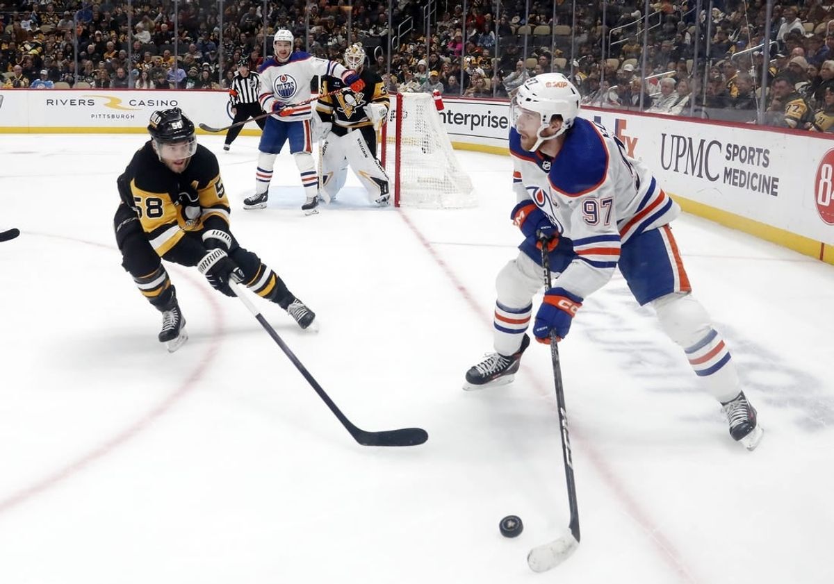 Mar 10, 2024; Pittsburgh, Pennsylvania, USA;  Edmonton Oilers center Connor McDavid (97) moves the puck against the Pittsburgh Penguins defenseman Kris Letang (58) during the second period at PPG Paints Arena.