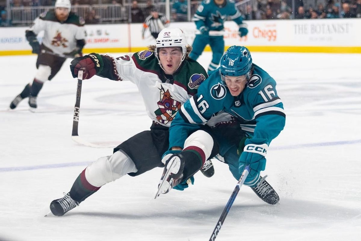 Dec 21, 2023; San Jose, California, USA; Arizona Coyotes center Logan Cooley (92) and San Jose Sharks center Jack Studnicka (16) collides during the first period at SAP Center at San Jose.