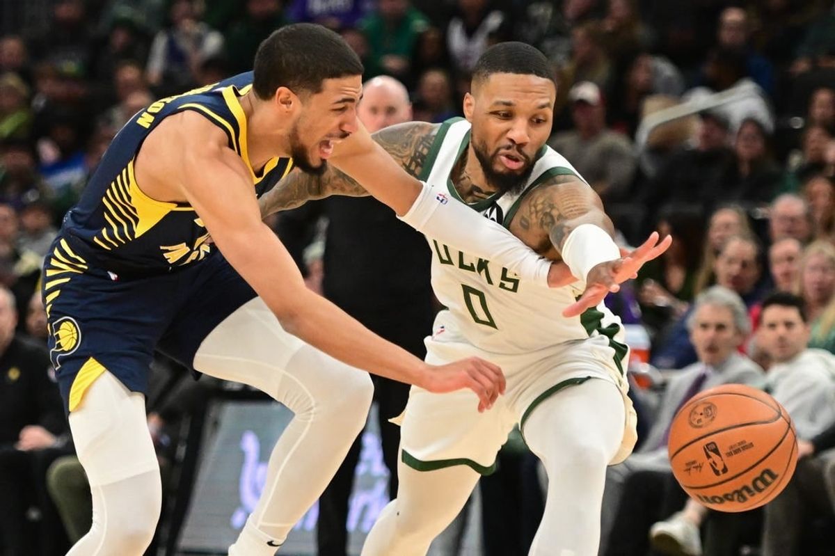 Dec 13, 2023; Milwaukee, Wisconsin, USA; Indiana Pacers guard Tyrese Haliburton (0) and Milwaukee Bucks guard Damian Lillard (0) reach for a loose ball in the first quarter at Fiserv Forum.