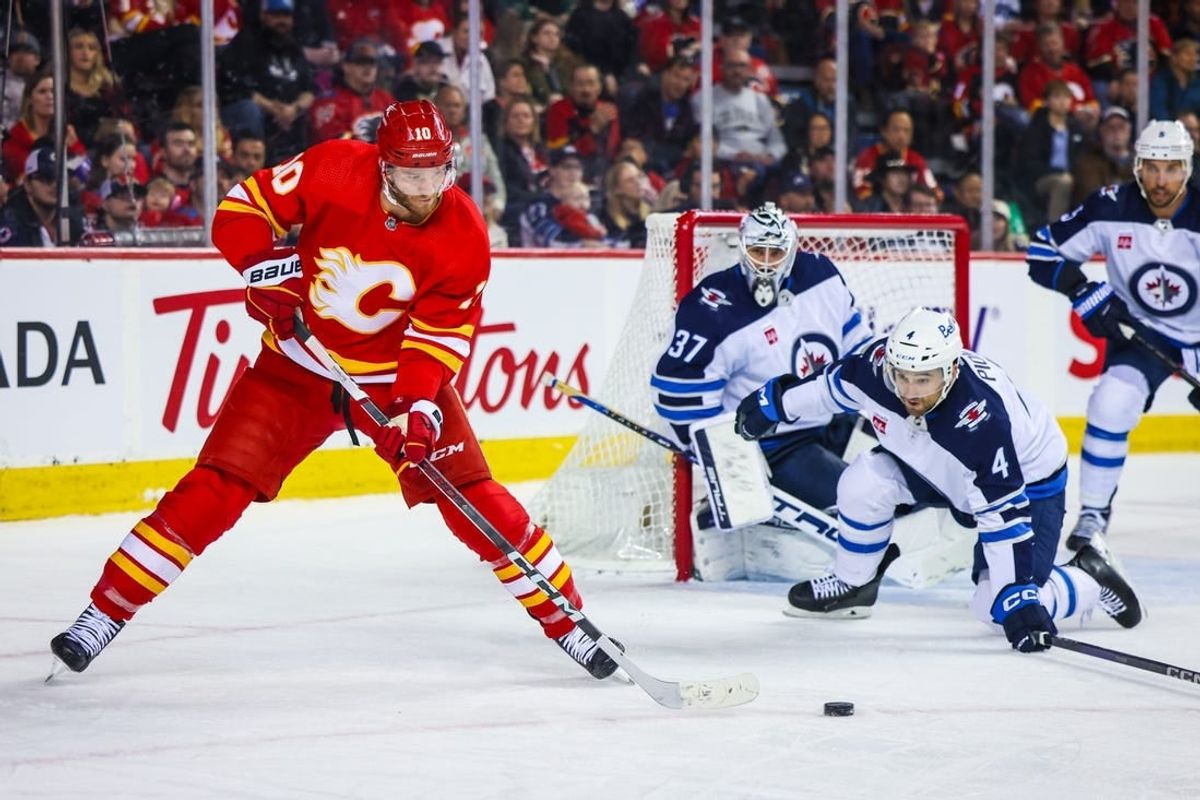 Feb 19, 2024; Calgary, Alberta, CAN; Calgary Flames center Jonathan Huberdeau (10) passes the puck against the Winnipeg Jets during the second period at Scotiabank Saddledome.