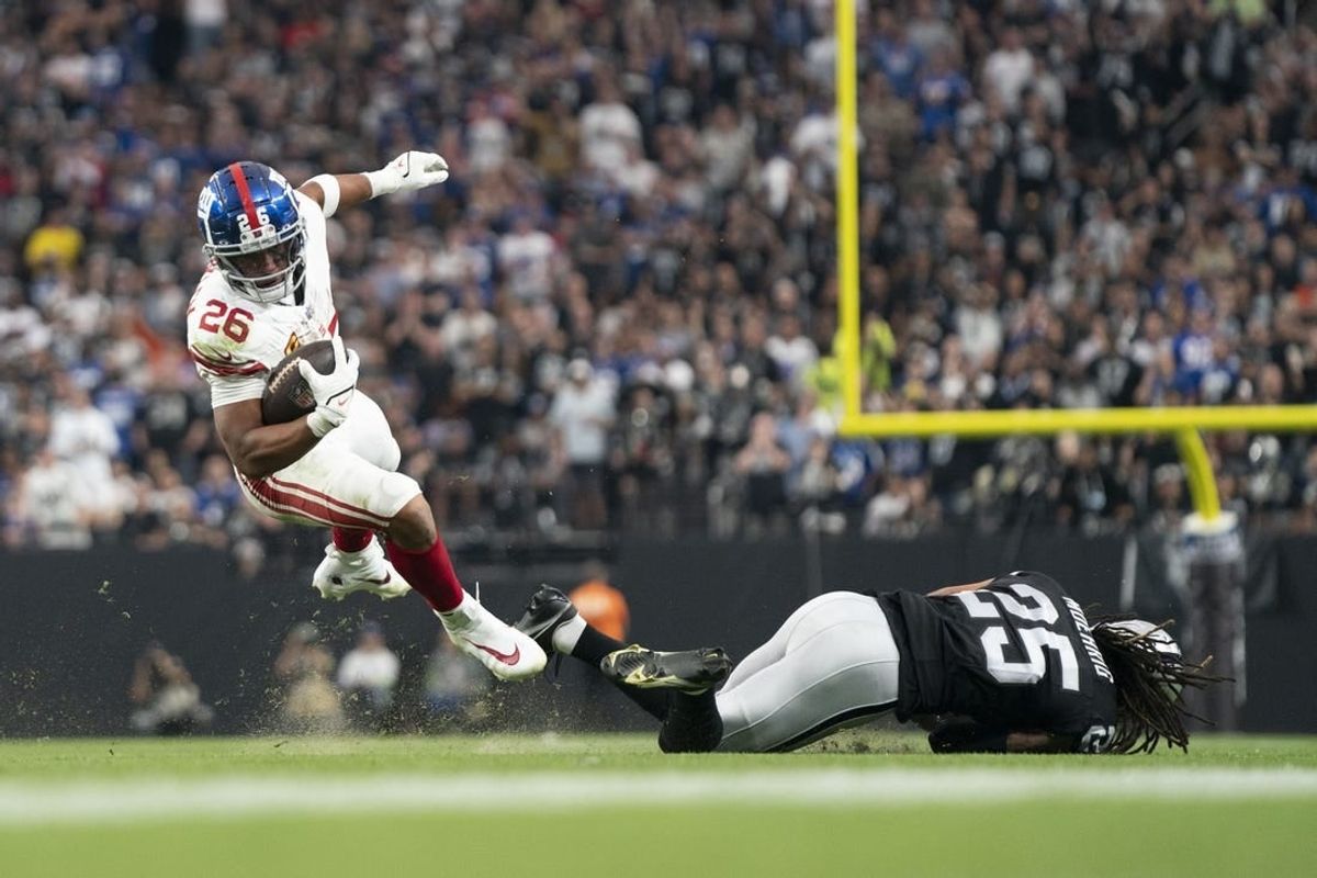 New York Giants running back Saquon Barkley (26) is tackled by Las Vegas Raiders safety Tre'von Moehrig (25) during the third quarter at Allegiant Stadium.