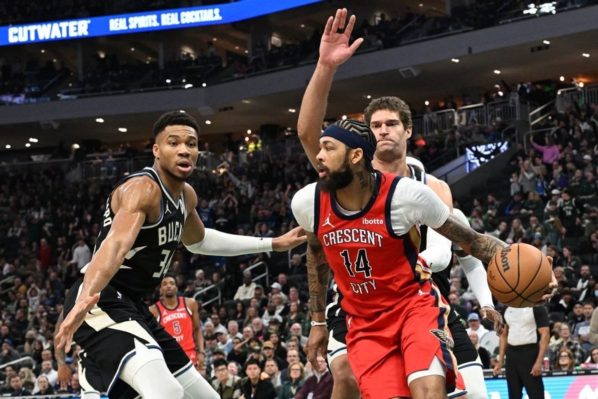 Jan 27, 2024; Milwaukee, Wisconsin, USA; New Orleans Pelicans forward Brandon Ingram (14) dribbles against Milwaukee Bucks forward Giannis Antetokounmpo (34) and Milwaukee Bucks center Brook Lopez (11) in the first half at Fiserv Forum.