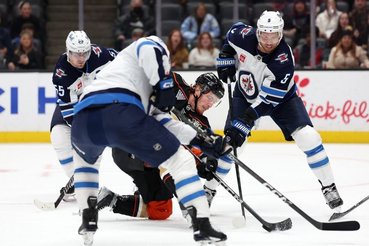 Dec 10, 2023; Anaheim, California, USA;  Anaheim Ducks left wing Brock McGinn (26) fights for the puck against Winnipeg Jets defenseman Brenden Dillon (5) during the second period at Honda Center.