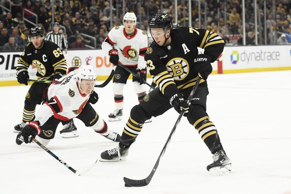 Apr 16, 2024; Boston, Massachusetts, USA;  Boston Bruins defenseman Charlie McAvoy (73) controls the puck while Ottawa Senators left wing Brady Tkachuk (7) defends during the third period at TD Garden.