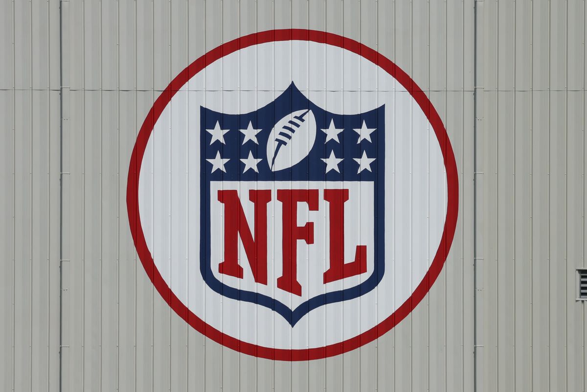A red, white, and blue NFL logo is shown painted on the side of a corrugated metal building.