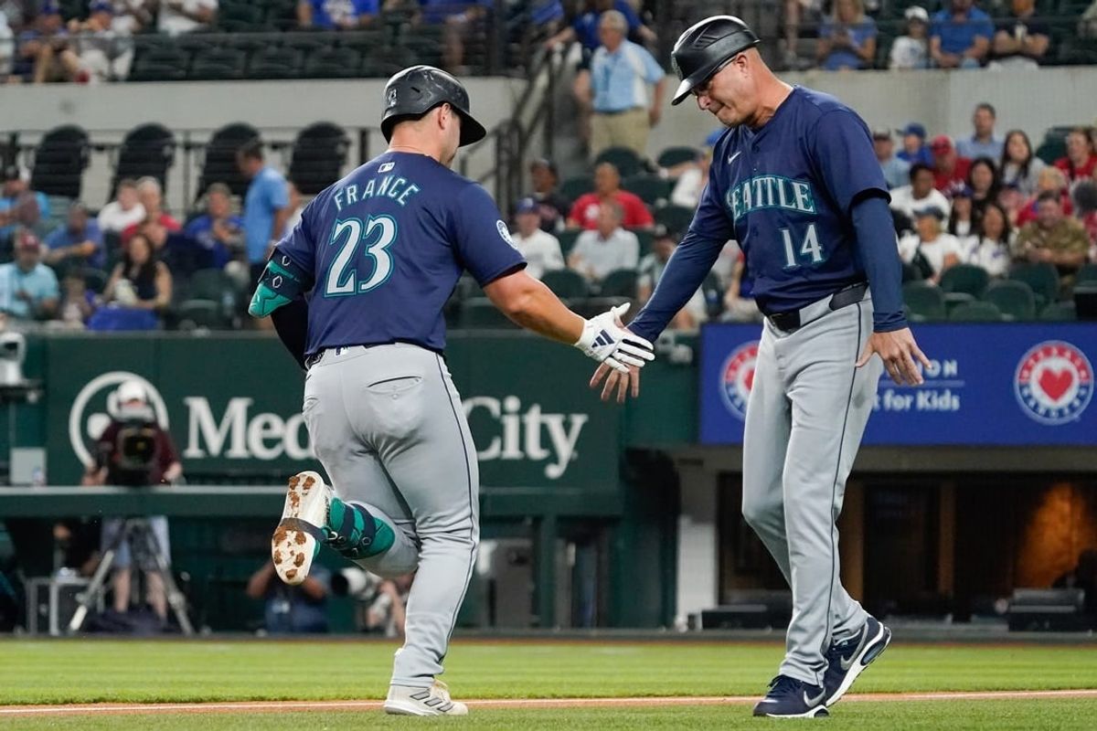 Apr 25, 2024; Arlington, Texas, USA; Seattle Mariners first baseman Ty France (23) slaps the hand of third base coach Manny Acta (14) after hitting a two-run home run during the first inning against the Texas Rangers at Globe Life Field.
