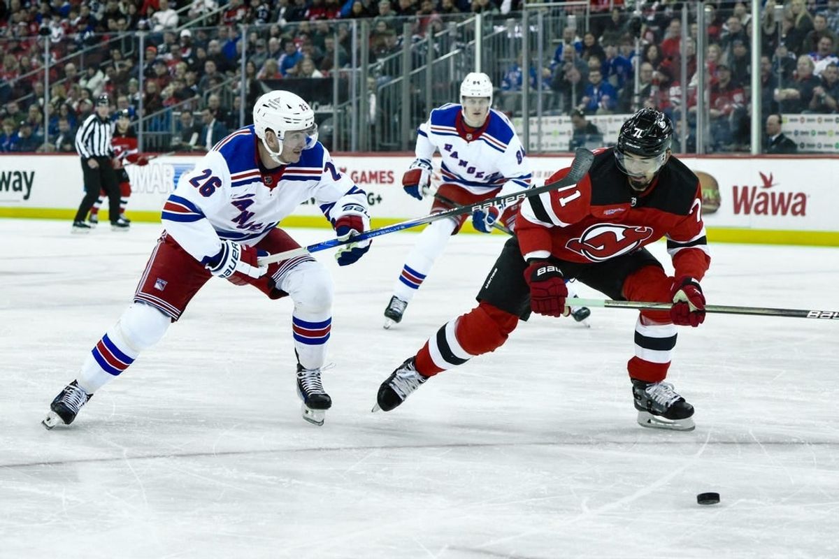 Feb 22, 2024; Newark, New Jersey, USA; New Jersey Devils defenseman Jonas Siegenthaler (71) and New York Rangers left wing Jimmy Vesey (26) pursue the puck during the first period at Prudential Center.